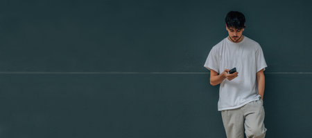 young man on wall with mobile phone and casual outfitの写真素材