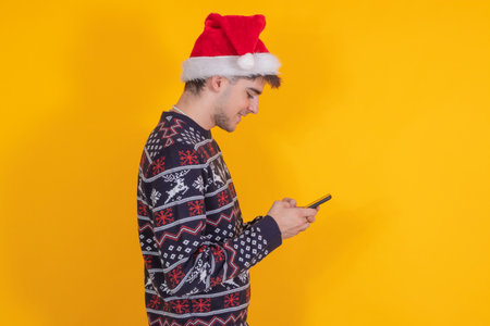 isolated young man with santa claus hat and mobile phoneの写真素材