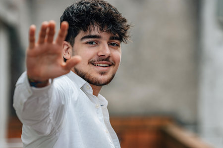 portrait of young man in the street saying goodbye or greetingの写真素材