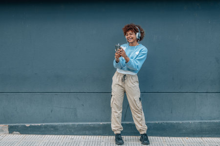 girl on the street with mobile phone and headphones full lengthの写真素材