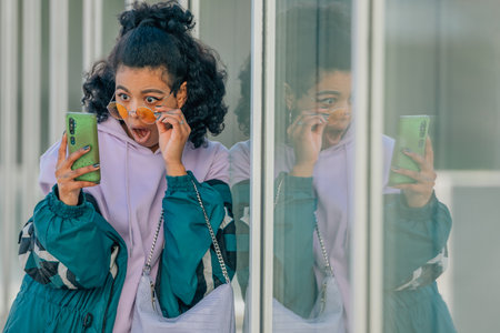 trendy urban style girl with mobile phone and surprised expressionの写真素材