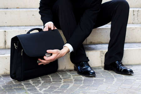 man sitting in the stairs open the professional bagの写真素材