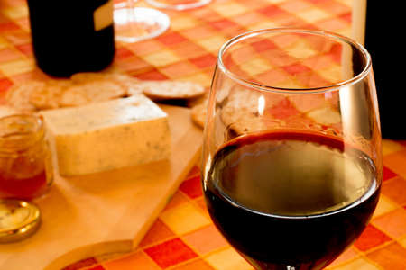 Glass of red wine, cheese, bread, in the rustic tableの写真素材