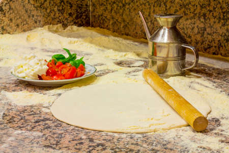 Make a typical italian food, dough, cheese, tomato, basil, flourの写真素材