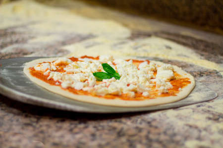 machining of the pizza. Italian pizza chef puts on the blade pizza and bakeの写真素材