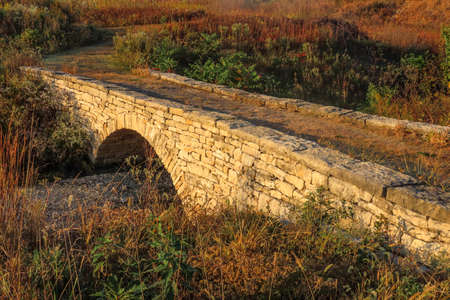 stone bridge with arch on rural hiking path over dry creek, Kansas