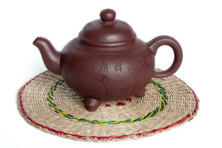 The Chinese teapot from clay on the straw napkin. Isolated on white.の写真素材