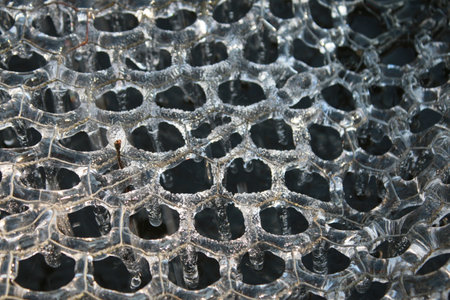 Close up of frozen water in freezing Winter weather white transparent pattern of hexagons on metal...