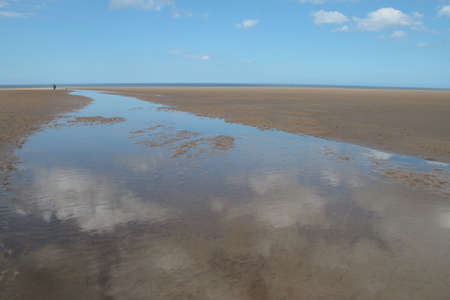 Landscape of beautiful sandy beach with no people and sands stretched to horizon with white puffy...