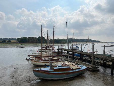 Landscape of boats in beautiful estuary water with sail boats moored in muddy beach by shore in Woodbridge Suffolk Eat Anglia with cloudy sky reflected in the river Summer holidayのeditorial素材