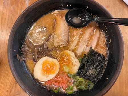 Japanese noodle soup in black bowl on wooden table.の写真素材