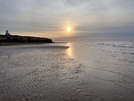 Beautiful sunset beach jurassic cliff sandy landscape at Hunstanton Norfolk uk in early evening light with colourful sky reflected in sea ocean water on shore peaceful environmentの写真素材