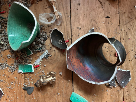 Close up of broken ceramic art and antique china vase and plates of different shape and colour pieces destroyed by fall from collapsed mantelpiece to oak wood floor in old houseの写真素材