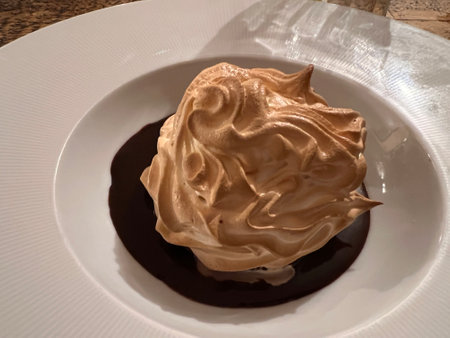 Meringue with chocolate on a white plate on a wooden table