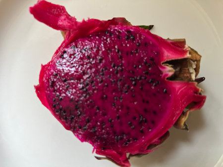 Close up of Dragon fruit Pitahaya delicious edible ripe juicy healthy eating red fruit with black seeds and leaves in close-up, top view on white china plateの写真素材