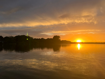 Sunset over the lake with reflection in the water and trees.の写真素材