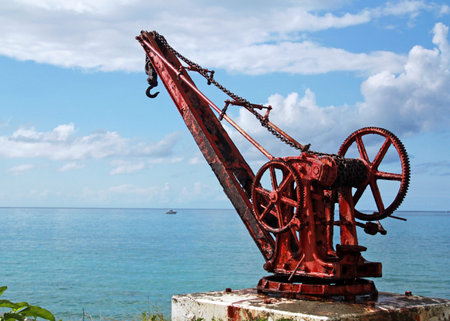 Old rusty crane on the sea shore with blue sky and white clouds