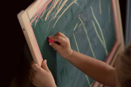 little kid is drawing on blackboardの写真素材