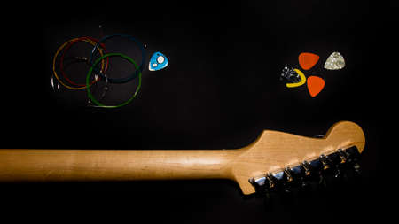 electric guitar neck (rear view), multicolor strings and picks on black backgroundの写真素材