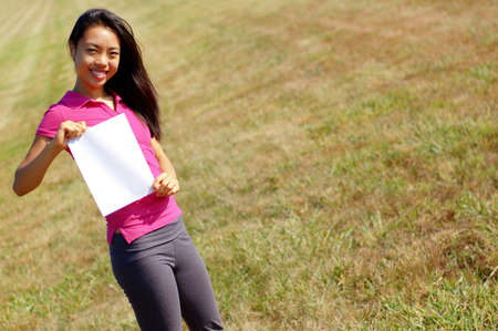 Girl in field holding a blank sign.の写真素材