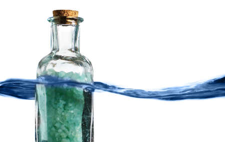 Bottle of bath salts sitting in a blue wave of water.の写真素材