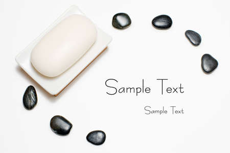 Soap dish and black rocks against a white background.の写真素材