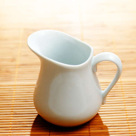 White pitcher on display against a bamboo mat.の写真素材