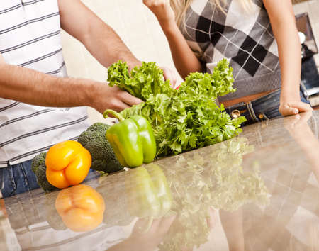 Cropped view of a young couple stand behind a kitchen counter full of vegetables. Horizontal shot.の写真素材