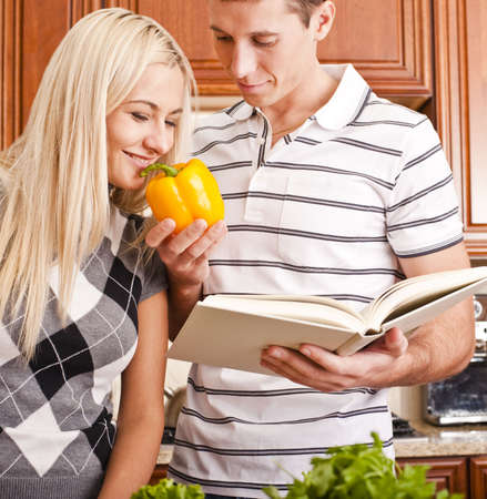 Young man with cook book holding yellow pepper for young woman to smell. Vertical shot.の写真素材