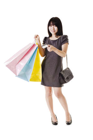 Beautiful Chinese woman with shopping bags and credit card in front of a white background.の写真素材