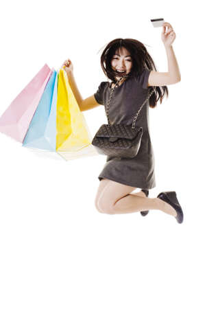 Chinese woman with shopping bags, purse, and credit card jumping into the air.の写真素材