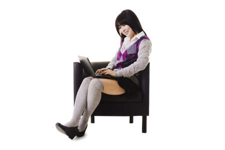 Chinese student working on a laptop and sitting in a chair.の写真素材