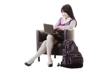 Chinese student sitting in a leather chair with a laptop working.の写真素材