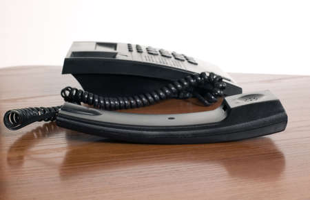 There is a black telephone on brown table