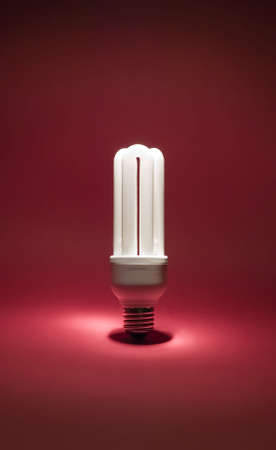 Electric bulb on red background with white lightの写真素材