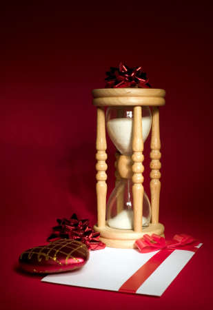 Sand clock with with white envelope on red background