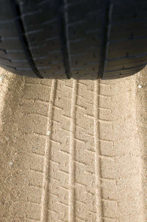 There is a black tyre and track of it on sandの写真素材