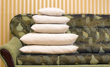 Many pillows on green couch with yellow backgroundの写真素材