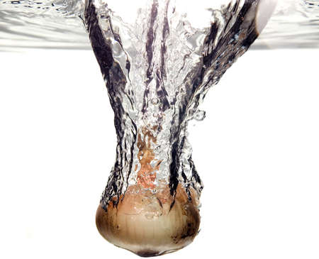 Orange vegetable onion is dropped into waterの写真素材