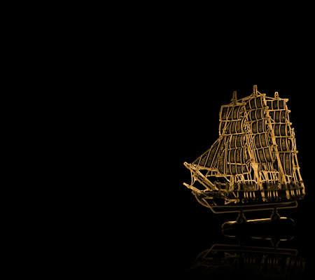 Golden antique ship with reflection on black backgroundの写真素材