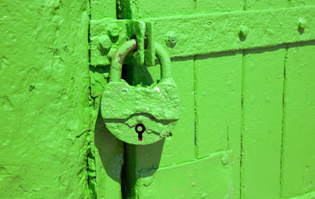 Green metal lock is hanging to protect entrance through doorsの写真素材