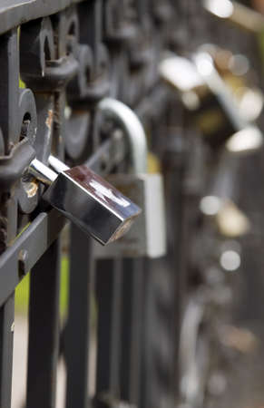 Many metal locks are hanging on black fence, security conceptの写真素材