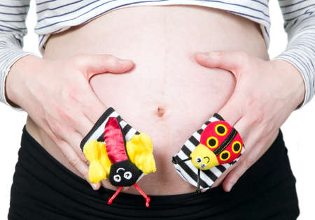 Pregnant woman hands holding colorful baby socksの写真素材