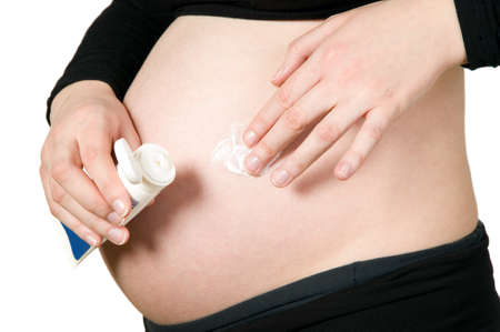 Pregnant woman massage her pregnant belly with a cream