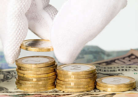 Man with white gloves is putting coins one on other