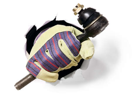 Man with gloves is holding tools through a hole in white paper