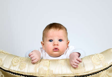 Baby boy is watching through a top of vintage chairの写真素材