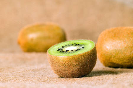 Green fruit kiwi cut and placed on brown background, food conceptの写真素材