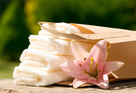 White towels placed in paper bag with pink flower and green backgroundの写真素材