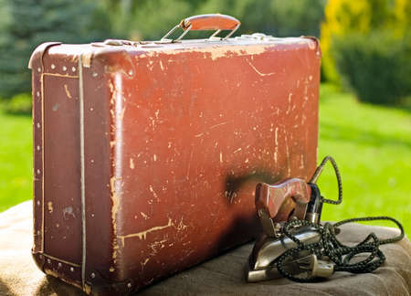 Vintage old brown suitcase on green nature background